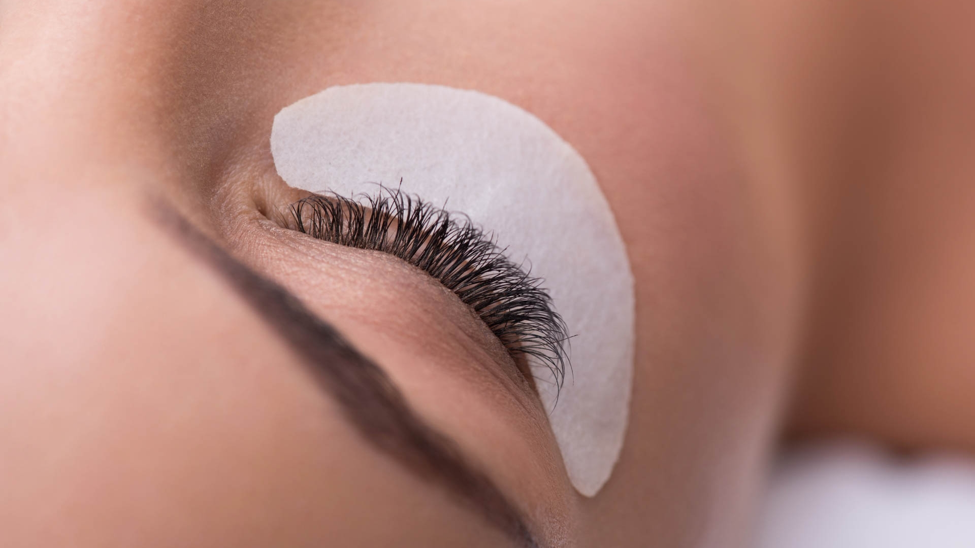 Close up of female closed eye with artificial lashes over small special paper